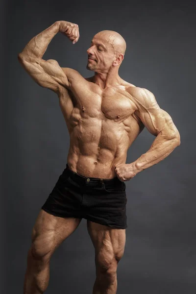 Profesional fuerte culturista atlético hombre posando bíceps delanteros en estudio —  Fotos de Stock