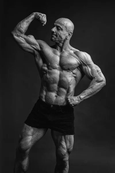 Profissional forte fisiculturista atlético homem posando frente bíceps em estúdio — Fotografia de Stock