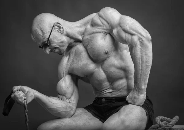 Bodybuilder professionnel posant tout en étant assis avec la bande de résistance — Photo