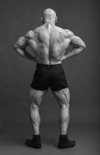 Atleet in terug lat verspreid pose. Bodybuilder spieren waarop studio achtergrond — Stockfoto