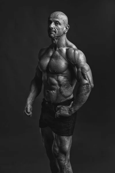 Professijnal bodybuilder och erb modell poserar bröst, biceps och sex-pack abs. svartvitt låg nyckel version. — Stockfoto