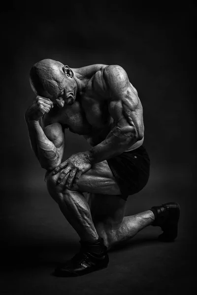 Bodybuilder professionnel et modèle fitnes posant en studio comme un philosophe. Version basse kay noir et blanc . — Photo