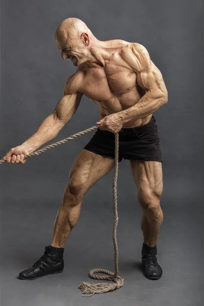 Athletic man with great physique pulling rope and smiling — Stock Photo, Image