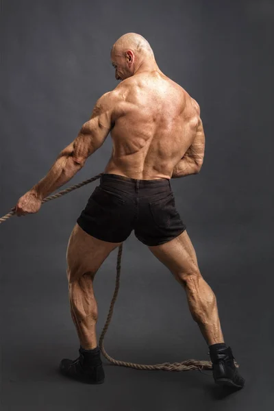 Achteraanzicht van atletische man met grote lichaamsbouw touw trekken. — Stockfoto