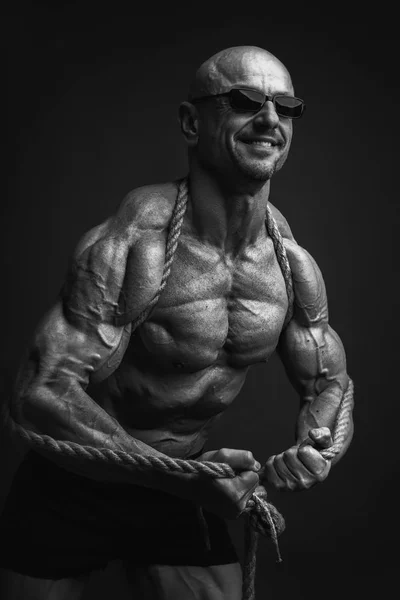 Ritratto di uomo atletico muscoloso in occhiali da sole con una corda sulla spalla . — Foto Stock