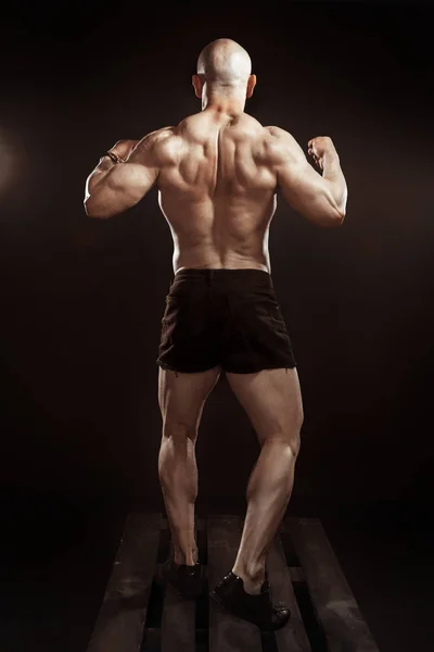 Bodybuilder shows back muscles in studio — ストック写真