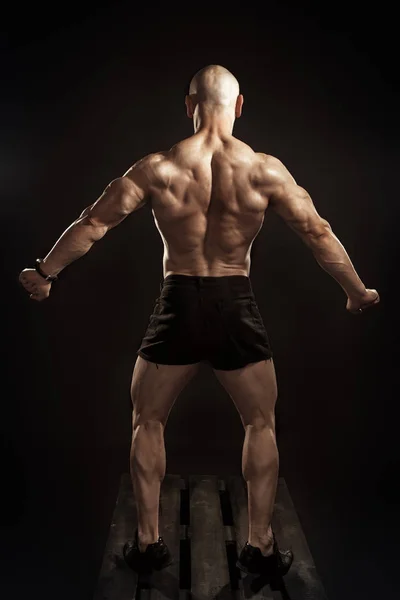 Bodybuilder shows back muscles in studio — ストック写真