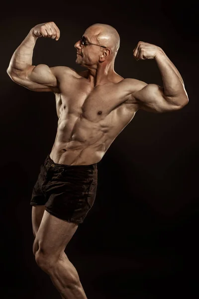 Retrato de fitness de fisiculturista careca com perfeito pacote de seis mostrando bíceps duplo . Imagens Royalty-Free