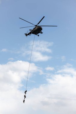 Soldiers go down a rope from military helicopter.