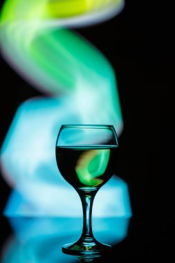 Karanlık, güzel bir arka planda aydınlanmış bir bardak. 