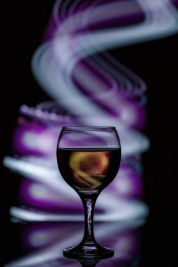 Karanlık, güzel bir arka planda aydınlanmış bir bardak. 