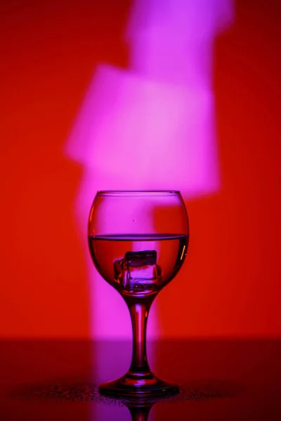 A glass with a drink on a beautiful red background illuminated w — ストック写真