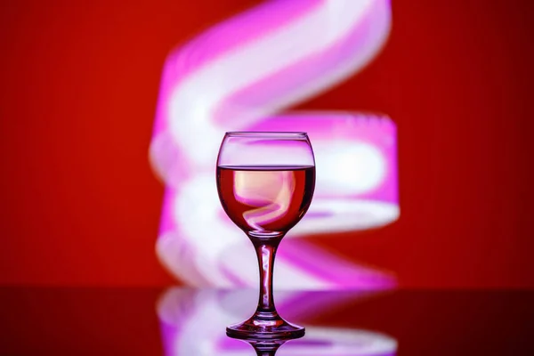 A glass with a drink on a beautiful red background illuminated w — ストック写真