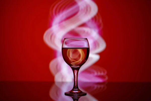 Güzel, kırmızı bir arka planda içkisi olan bir bardak. — Stok fotoğraf