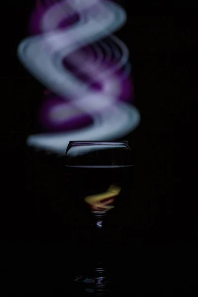 A glass with a drink on a dark beautiful background illuminated — Stock Photo, Image