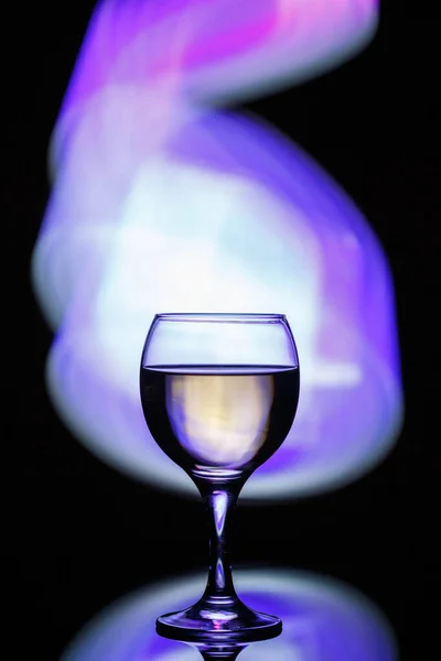 Szklankę z napojem na ciemnym, pięknym tle oświetlonym — Zdjęcie stockowe