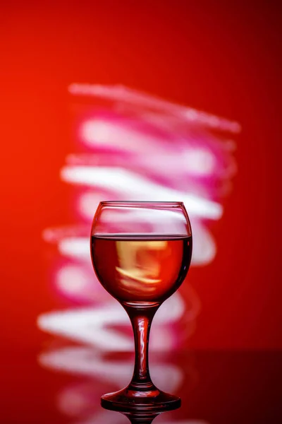 A glass with a drink on a beautiful red background illuminated w — ストック写真