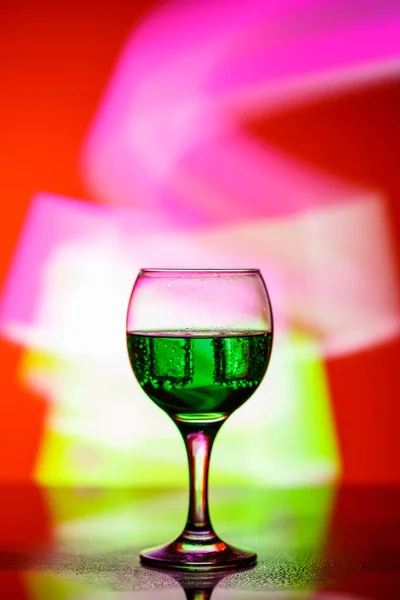 Sklenice s nápojem na krásném červeném pozadí osvětlené w — Stock fotografie