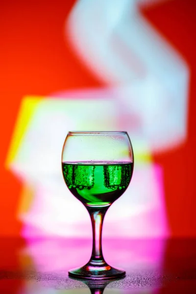 A glass with a drink on a beautiful red background illuminated w — ストック写真