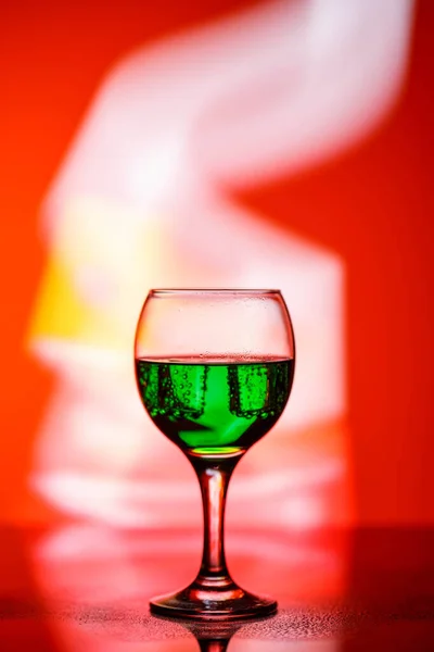 A glass with a drink on a beautiful red background illuminated w — ストック写真