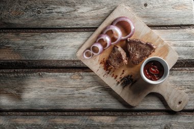 Baharatlı ızgara et ve aşınmış ahşap bir sırt üzerinde domates sosu.