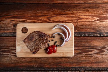 Baharatlı ızgara et ve aşınmış ahşap bir sırt üzerinde domates sosu.