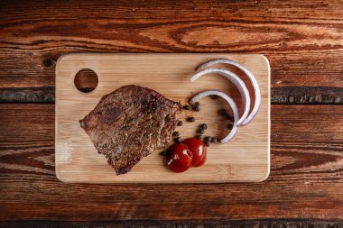 Baharatlı ızgara et ve aşınmış ahşap bir sırt üzerinde domates sosu.