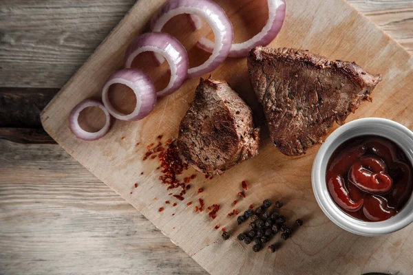 Grillat kött med kryddor och tomatsås på en sliten träbakdel — Stockfoto
