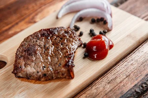 Grillat kött med kryddor och tomatsås på en sliten träbakdel — Stockfoto