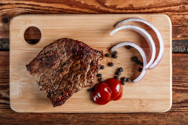 Grillat kött med kryddor och tomatsås på en sliten träbakdel — Stockfoto