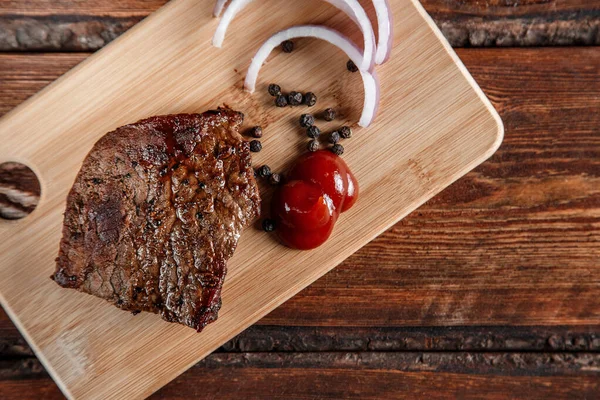 Grillat kött med kryddor och tomatsås på en sliten träbakdel — Stockfoto