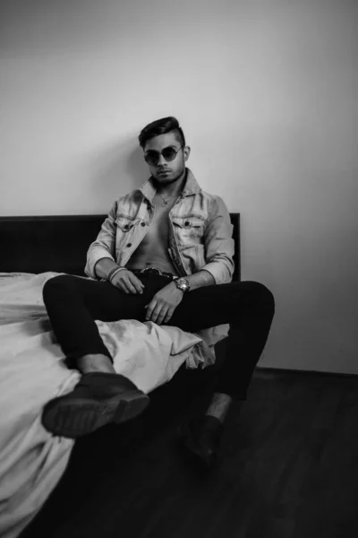 Jonge stijlvolle man met spijkerjasje op het bed. zwart-wit ph — Stockfoto