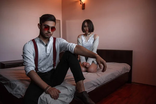 Un chico joven y elegante en gafas y una chica joven sentados juntos —  Fotos de Stock