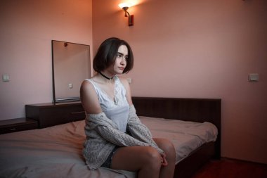 Süveter ve kot etekli kısa saçlı genç bir kız oturuyor.