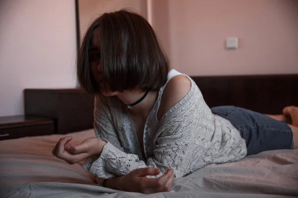 Νεαρή κοπέλα με κοντά μαλλιά σε ένα πουλόβερ, τζιν φούστα ξαπλωμένη μόνη της — Φωτογραφία Αρχείου