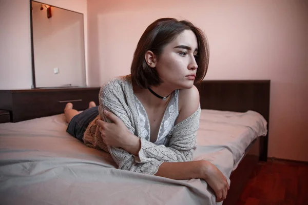 Jovem com cabelo curto em uma camisola, saia jeans deitado sozinho — Fotografia de Stock