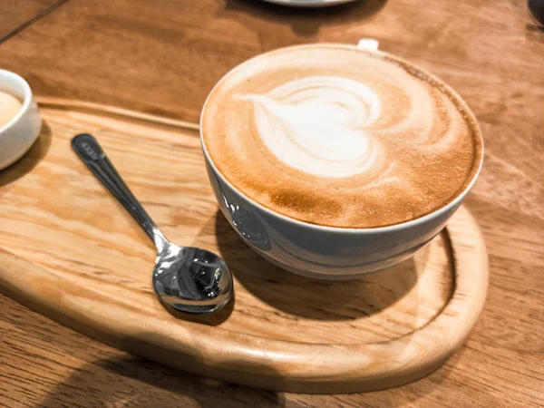 Cappuccino i en hvit keramikkkopp på et trefat. selektiv fo – stockfoto