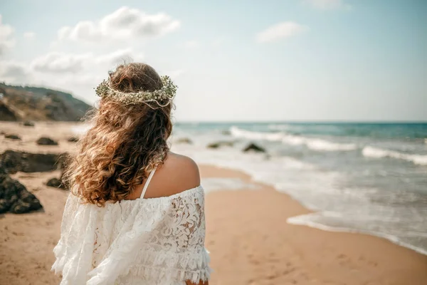 Eine Braut in einem weißen Brautkleid am Strand mit einem Blumenkranz auf dem Kopf. Blick von hinten — Stockfoto