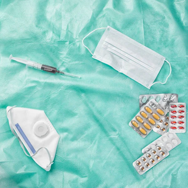 Medicamentos em embalagens, máscaras médicas descartáveis e amostras de sangue em uma seringa. em um fundo verde médico — Fotografia de Stock