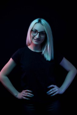 Gülümseyen beyaz tenli, gözlüklü güzel sarışın kadın. Neon ışıkta yakın plan portre