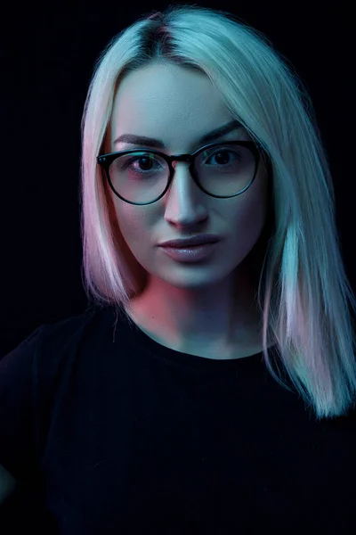 Задумчивая молодая белая блондинка в очках. портрет крупным планом в неоновом свете — стоковое фото