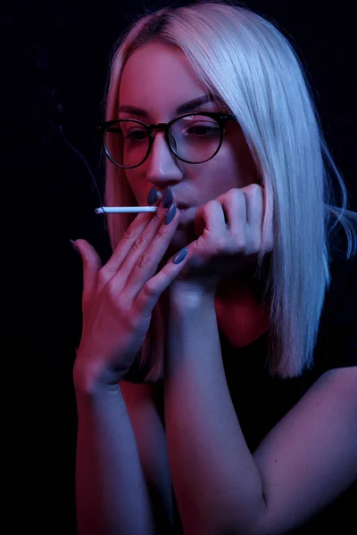 Jeune Caucasien belle femme blonde avec des lunettes Fumer. portrait en gros plan au néon — Photo