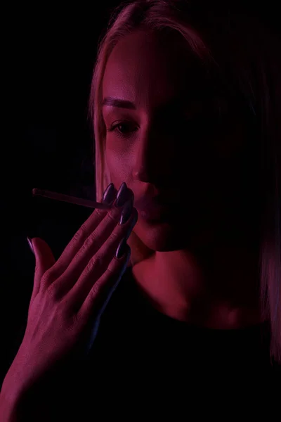 若い白人の美しいブロンドの女性喫煙.ネオンライトのクローズアップ肖像画 — ストック写真