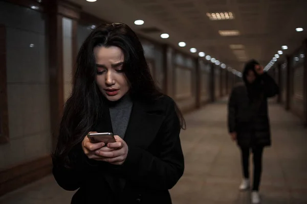 Genç ve güzel bir kadın gece vakti bir yeraltı geçidinde yürür, arkasında da başında başlık olan koyu renk elbiseli bir adam. Bir kadın, telefondaki kurtarma servisinin numarasını çevirmeye çalışıyor.