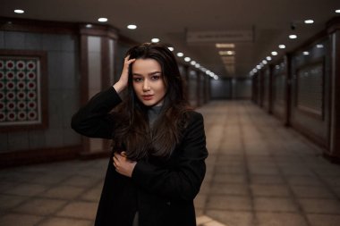 Yeraltı geçidinde siyah ceketli güzel bir kadının dramatik portresi. Duvarlardaki mozaikler kimsenin sanat eseri değil. Bunlar doğu tarzında bir yeraltı geçidinde duvarlar.