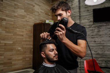 Vahşi görünümlü bir berber Hintli bir adamın saçını kesiyor. Sinematik görüntü