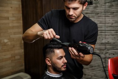 Vahşi görünümlü bir berber Hintli bir adamın saçını kesiyor. Sinematik görüntü