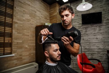 Vahşi görünümlü bir berber Hintli bir adamın saçını kesiyor. Sinematik görüntü