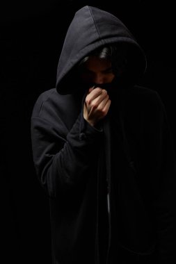  Siyah arka planda siyah kapüşonlu genç bir adamın yüzü kapalıydı..