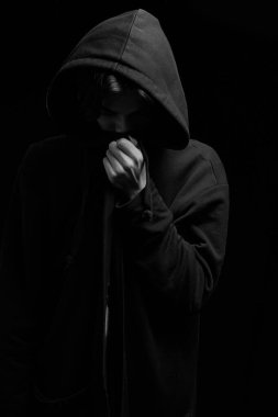  Siyah arka planda siyah kapüşonlu genç bir adamın yüzü kapalıydı..